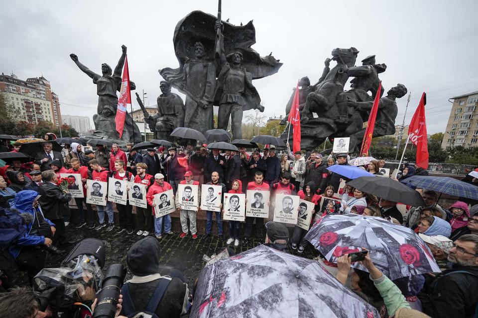 Personas con flores y retratos de los que perdieron la vida durante los sangrientos enfrentamientos de 1993 entre fuerzas gubernamentales y partidarios del Parlamento rebelde se reúnen para conmemorar el 30º aniversario de esos sucesos, frente al Monumento a los héroes de la Revolución de 1905, el miércoles 4 de octubre de 2023, en Moscú, Rusia. (AP Foto/Alexander Zemlianichenko)