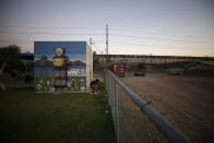 Gilberto Gil picks up a ball in a park as the border wall that separates Mexicali, Mexico from Calexico, Calif., sits in the distance, Tuesday, July 21, 2020, in Calexico. Imperial Valley is surrounded on three sides in the U.S. by vast, uninhabited desert and Mexicali's urban sprawl to the south. (AP Photo/Gregory Bull)