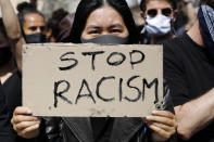 A woman shows a 'Stop Racism' sign as she attends a demonstration at the Alexander Platz in Berlin, Germany, Saturday, June 6, 2020, to protest against the recent killing of George Floyd by police officers in Minneapolis, USA, that has led to protests in many countries and across the US. A US police officer has been charged with the death of George Floyd. (AP Photo/Markus Schreiber)