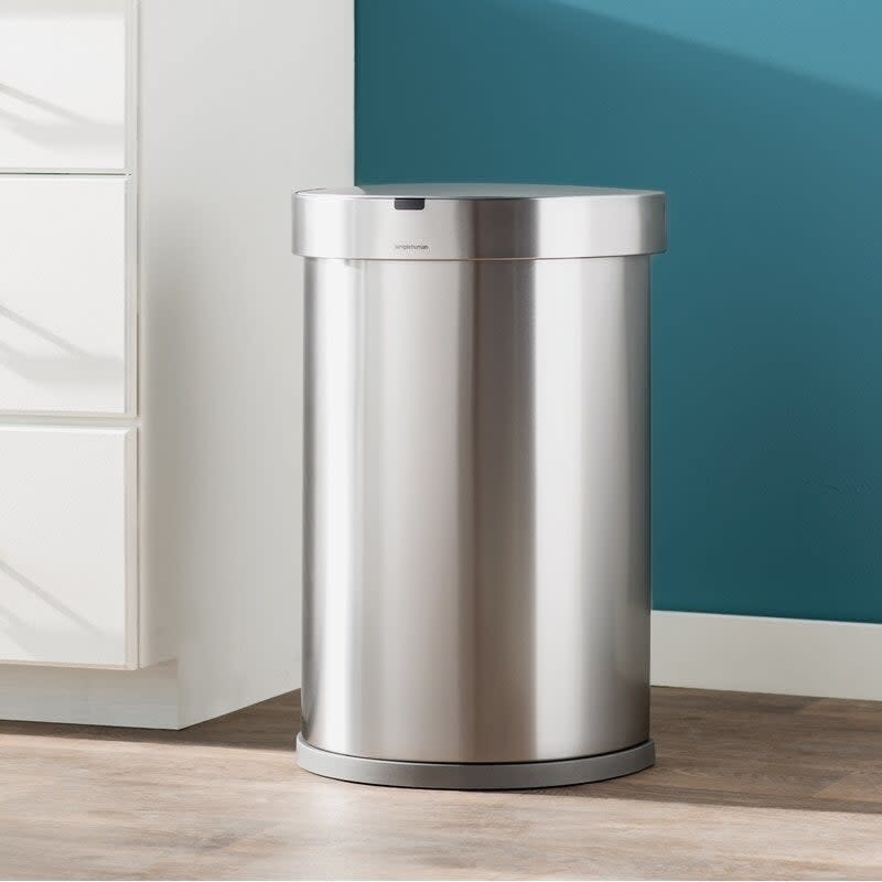 round stainless steel simplehuman trash can next to a wall