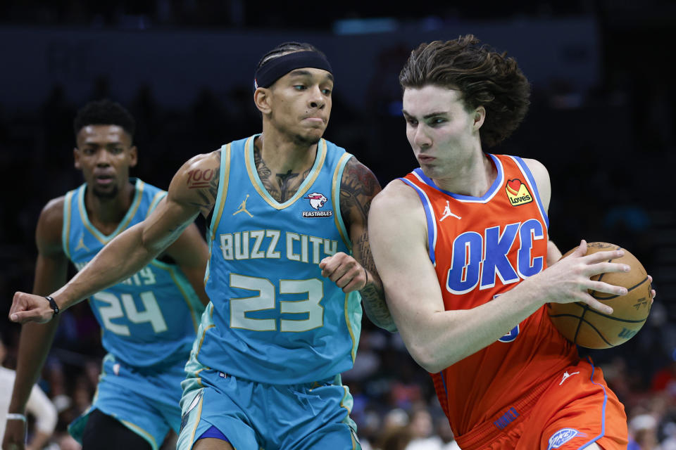 Oklahoma City Thunder guard Josh Giddey, right, drives against Charlotte Hornets guard Tre Mann (23) during the second half of an NBA basketball game in Charlotte, N.C., Sunday, April 7, 2024. (AP Photo/Nell Redmond)
