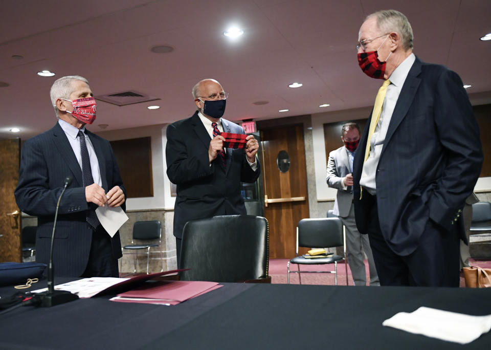 Dr. Anthony Fauci, director of the National Institute for Allergy and Infectious Diseases, left and Center for Disease Control (CDC) Director Dr. Robert Redfield, talk with Sen. Lamar Alexander, R-Tenn., right, as they prepare to testify before a Senate Health, Education, Labor and Pensions Committee hearing on Capitol Hill in Washington, Tuesday, June 30, 2020. (Kevin Dietsch/Pool via AP)