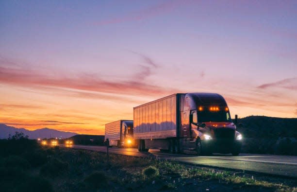 Large semi truck hauling freight on the open highway in the western USA under an evening sky.