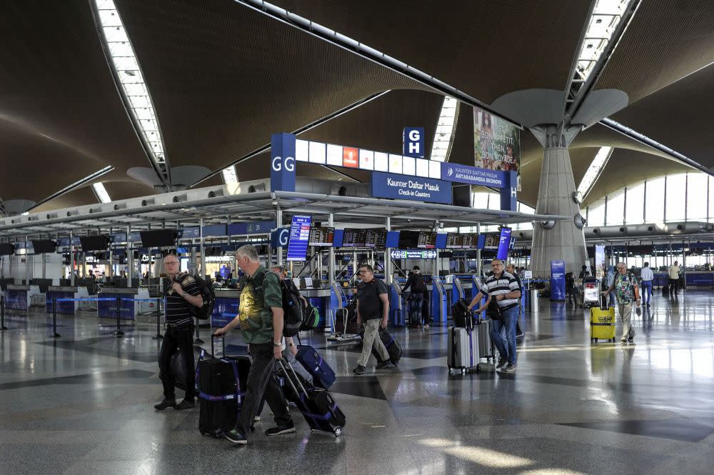 Travellers are pictured at the Kuala Lumpur International Airport in Sepang March 18, 2020. — Picture by Shafwan Zaidon