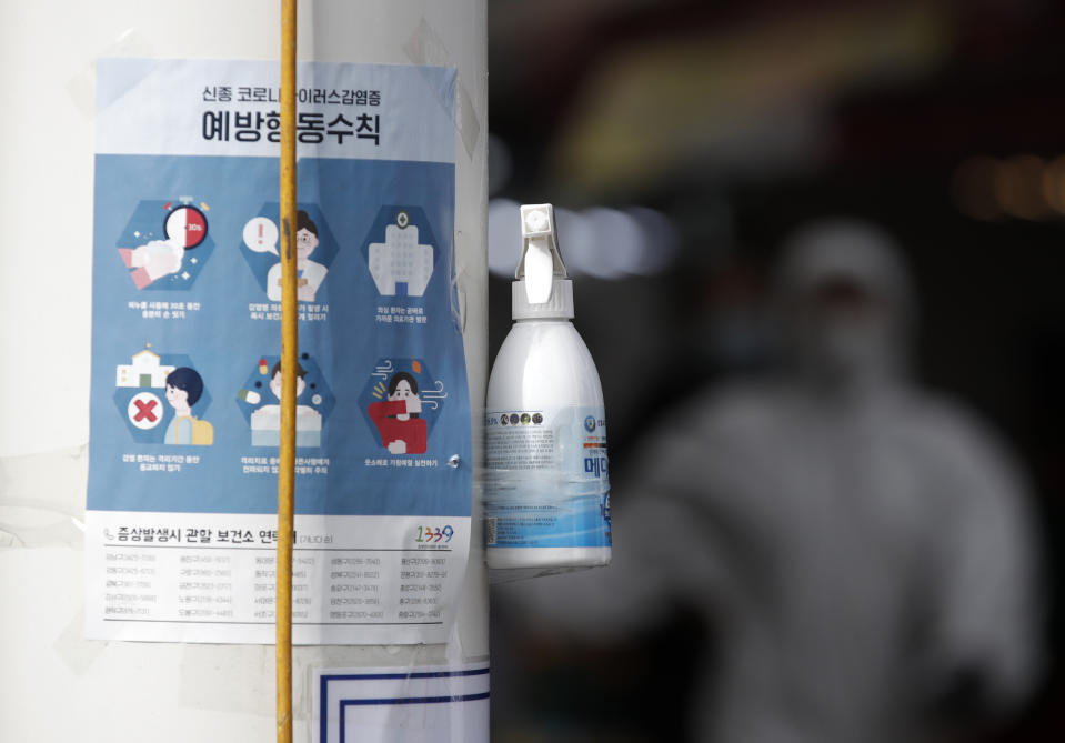 A bottle of hand sanitizers hangs on a pole on a street for visitors next to notices about precautions against the COVID-19 in front of a market in Seoul, South Korea, Wednesday, Feb. 26, 2020. The number of new virus cases in South Korea jumped again Wednesday and the first U.S. military soldier tested positive, with his infection and many others connected to a southeastern city where the outbreak has clustered. (AP Photo/Lee Jin-man)