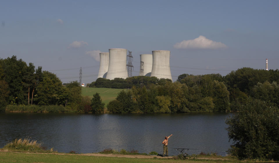 FILE - A man fishes with the towering Dukovany nuclear power plant in the background, in Dukovany, Czech Republic, Sept. 27, 2011. On Tuesday Oct. 31, 2023, three energy companies including U.S. Westinghouse, France's EdF and Korea's KHNP, have submitted their final bids to build the Czech Republic's newest reactor at the Dukovany nuclear power station as the country strives to become more energy independent and wean itself of fossil fuels. (AP Photo/Petr David Josek, File)