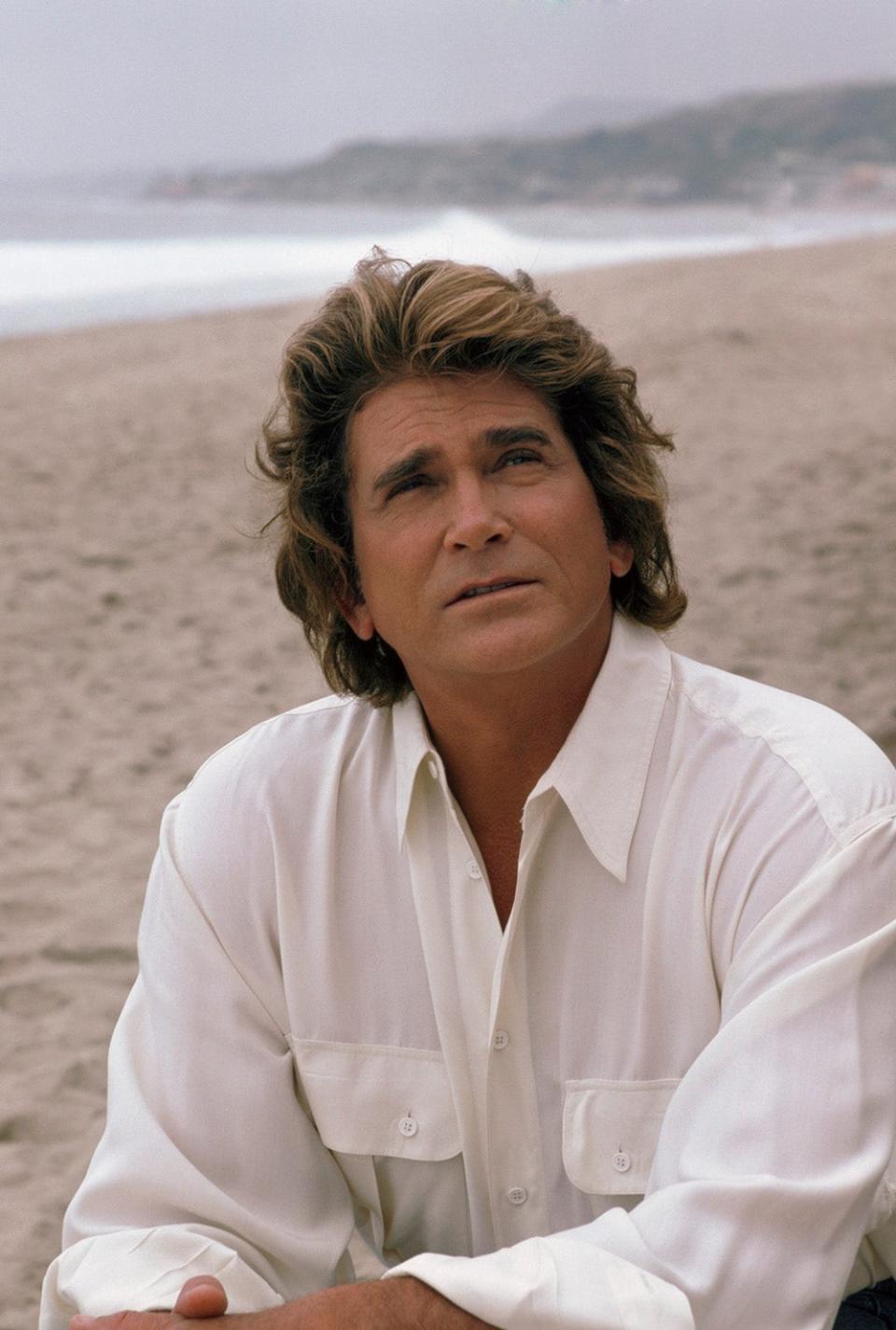 Michael Landon looking up at the sky wearing a white shirt.