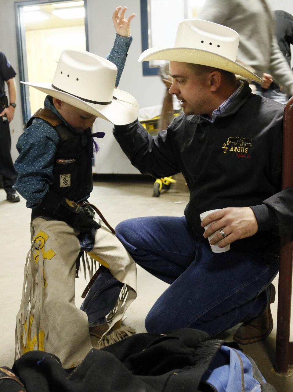 CeJay Jones practices holding on with his father Chris looking on before he competed in the mini bull riding competition at the 108th National Western Stock Show in Denver