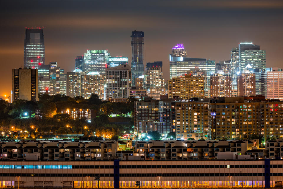 The Jersey City skyline rises behind in the dark.