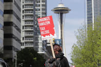FILE - In this May 1, 2020, file photo, a protester carries a sign that reads "Unionize Amazon Tax Bezos," in reference to Amazon founder and CEO Jeff Bezos, while riding a bike during a car-based protest at the Amazon Spheres in downtown Seattle. Mary's Place, a family homeless shelter located nearby inside an Amazon corporate building on the tech giant's Seattle campus, marks a major civic contribution bestowed by Amazon to the hometown it has rapidly transformed. But the Mary’s Place family homeless shelter also serves as a stark display of have-and-have-nots, given that some blame the tech giant's explosive growth over the past decade for making living in Seattle too costly for a growing number of people. (AP Photo/Ted S. Warren)