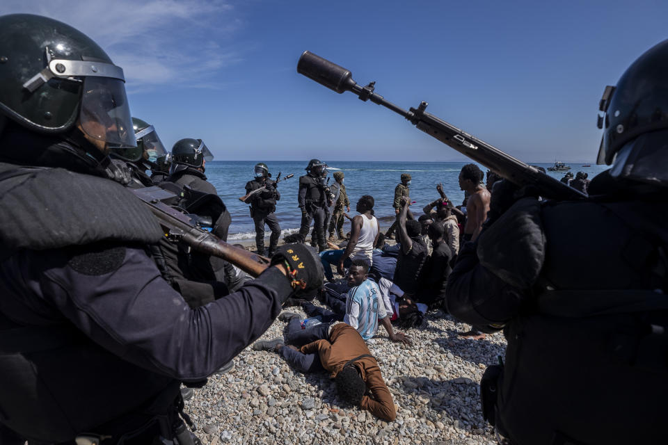 Migrants are surrounded by Spanish police near the border of Morocco and Spain, at the Spanish enclave of Ceuta, on Tuesday, May 18, 2021. (AP Photo/Bernat Armangue)