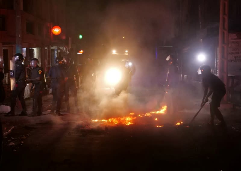 Riot police try to put out fire in the middle of the street during protests in Dakar