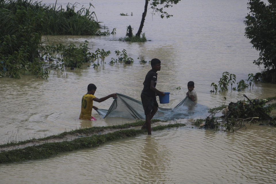 Rohingya refugees fish in flood waters following heavy rains at the Rohingya refugee camp in Kutupalong, Bangladesh, Wednesday, July 28, 2021. Days of heavy rains have brought thousands of shelters in various Rohingya refugee camps in Southern Bangladesh under water, rendering thousands of refugees homeless. (AP Photo/ Shafiqur Rahman)