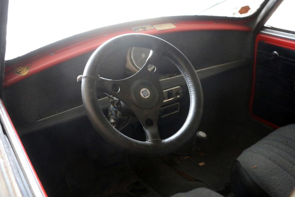 <p>A chunky steering wheel, and clear evidence of the car's original color being red.</p>