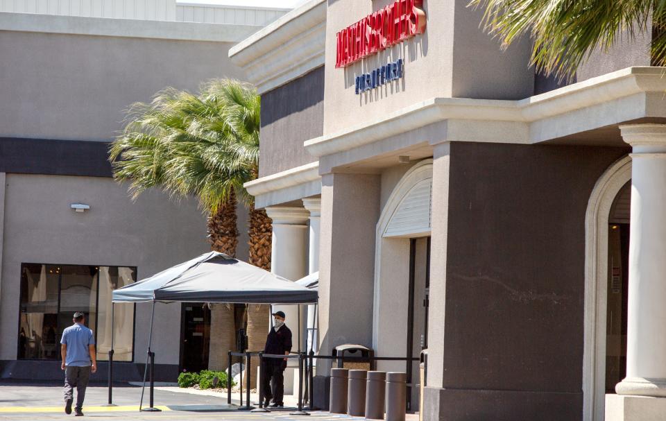 A shopper is directed to the temperature check point before entering Mathis Brothers Furniture in Indio, Calif., on Tuesday, April 14, 2020. 