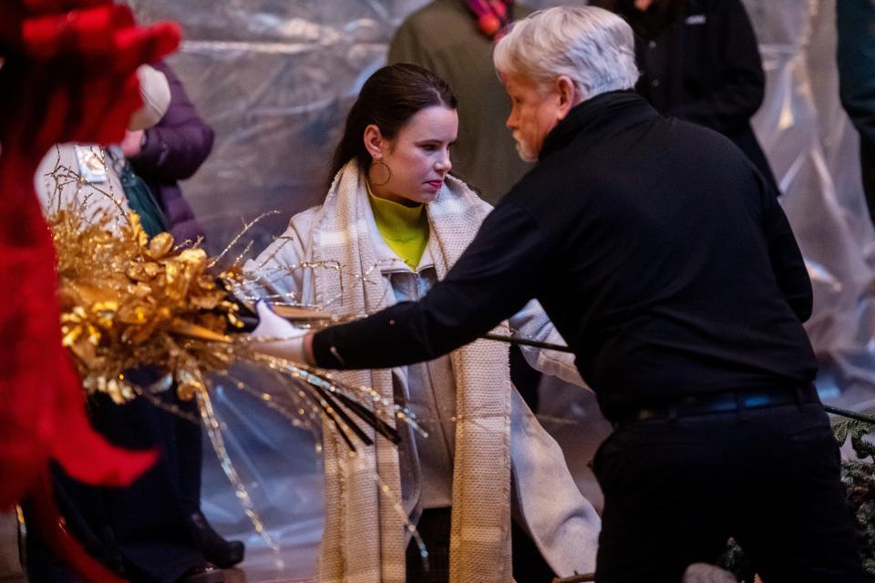 Lizzie Whitcher, Biltmore floral displays manager, and Don Holloway, decorator for the Banquet Hall, fix a golden decoration to the top of Biltmore’s Christmas tree before the tree is hoisted into place, November 1, 2023.