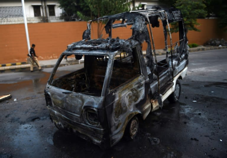 A Pakistani policeman walks past a torched police vehicle following a clash with activists of the Muttahida Qaumi Movement political party in Karachi on August 22, 2016 At least one person was killed and seven others were injured after activists of a political party clashed with police and ransacked a private television channel office in the southern Pakistani port city of Karachi, police said. The violence erupted soon after the influential MQM party ended its week-long hunger strike against a government crackdown targeting them