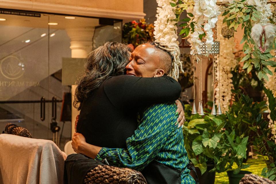 Two women hug in a plant store.