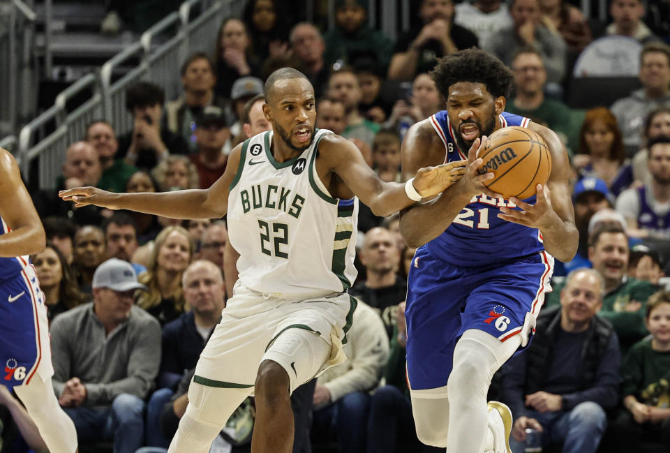 Philadelphia 76ers center Joel Embiid (21) and Milwaukee Bucks forward Khris Middleton (22) reach for the ball during the first half of an NBA basketball game Sunday, April 2, 2023, in Milwaukee. (AP Photo/Jeffrey Phelps)