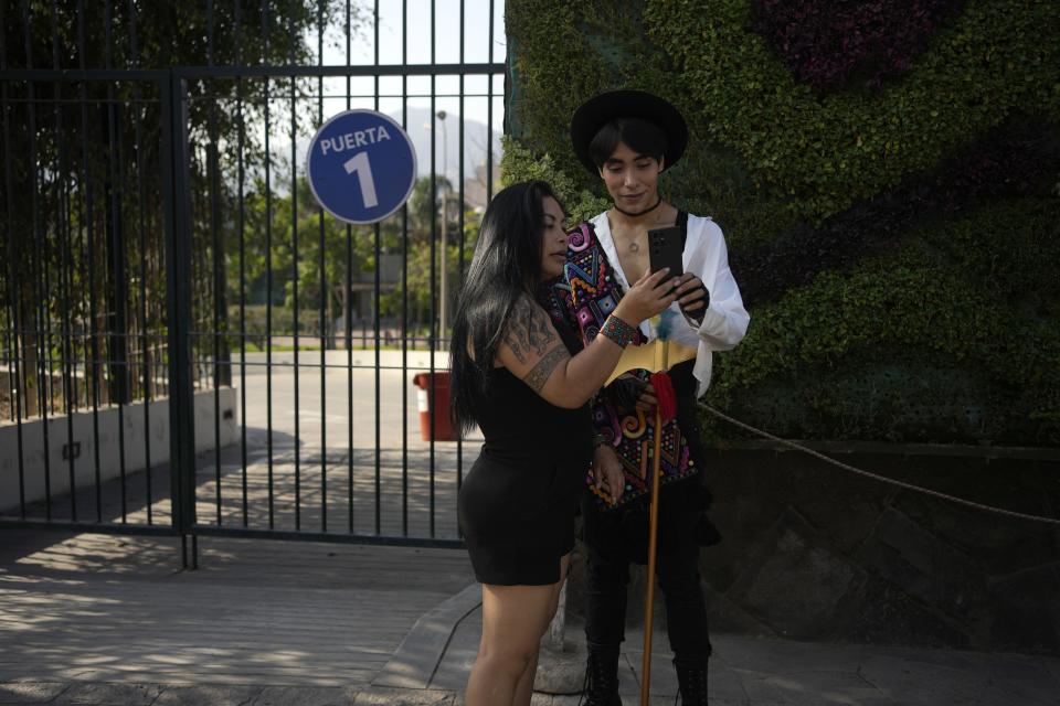 Peruvian singer Lenin Tamayo and his mother Yolanda Pinares, look at a cellphone during a break from recording a video in downtown Lima, Peru, Thursday, Aug. 3, 2023. With his fusion of K-pop and Andean culture, the 23-year-old composer is known as the inventor of Quechua pop or Q-pop, writing songs in Spanish and Quechua. (AP Photo/Martin Mejia)