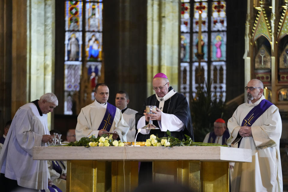 Prague Archbishop Jan Graubner, centre, holds the chalice during service for the victims of Philosophical Faculty of Charles University shooting in the St. Vitus Cathedral in Prague, Czech Republic, Saturday, Dec. 23, 2023. Czech police are investigating why a student went on a dayslong violent rampage culminating in a shooting at the university he attended in Prague that left 14 dead and dozens wounded. (AP Photo/Petr David Josek)