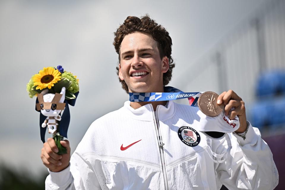 Eaton posing on the podium with his medal and flowers after the men's street prelims