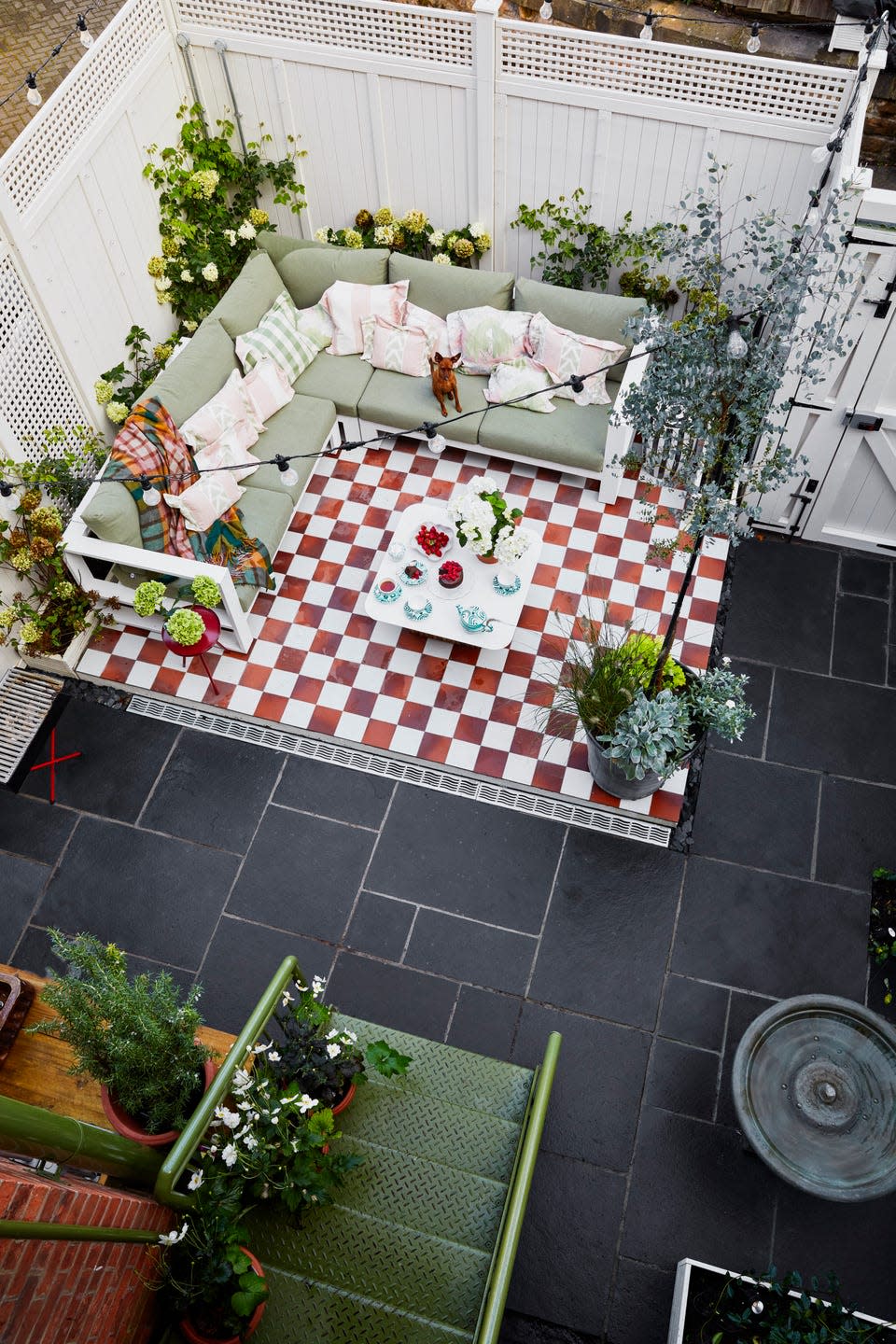 overhead of a garden with a chequerboard section of flooring with an outdoor sofa and coffee table