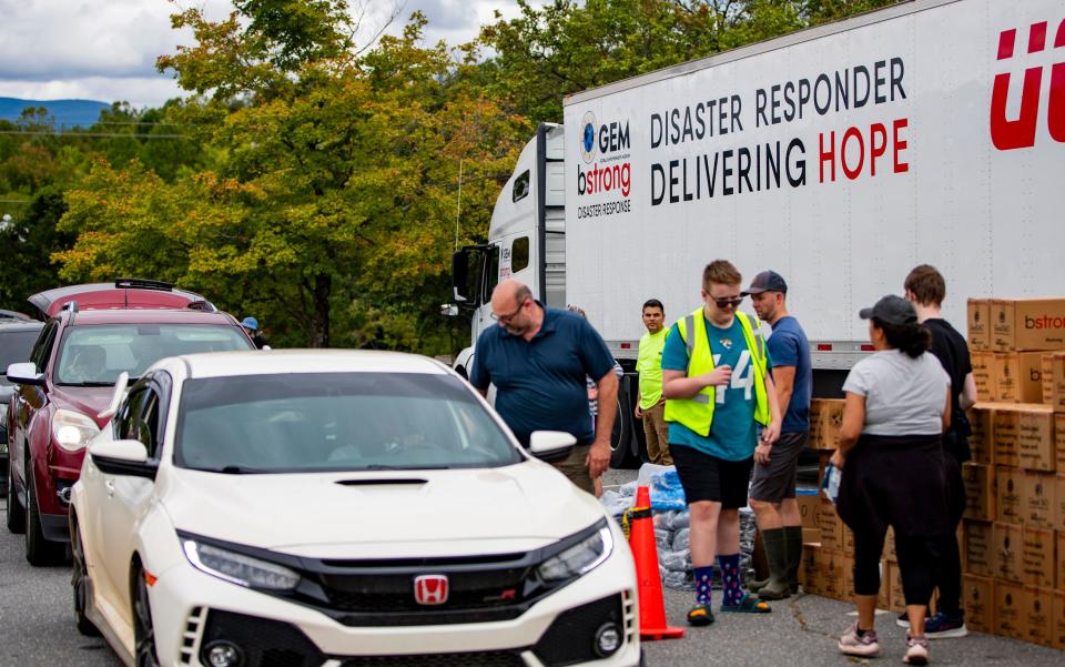 Volunteers load cars with food and other supplies during a food drive at the Asheville Mall Sunday afternoon in Asheville, NC.