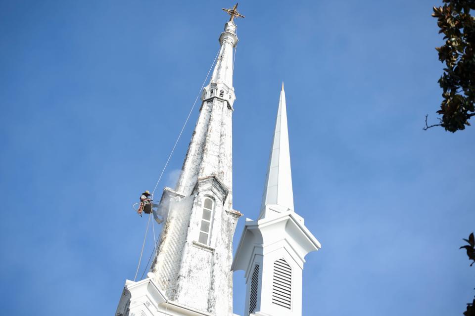 Steeplejack Fred Franklin pressure washes the steeple at First Christian Church.