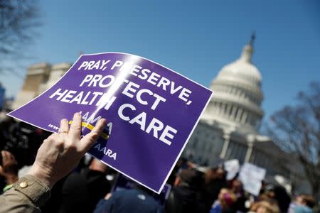 Demonstrators hold signs during a protest against the repeal of the Affordable Care Act outside the Capitol Building in Washington, U.S., March 22, 2017. REUTERS/Aaron P. Bernstein