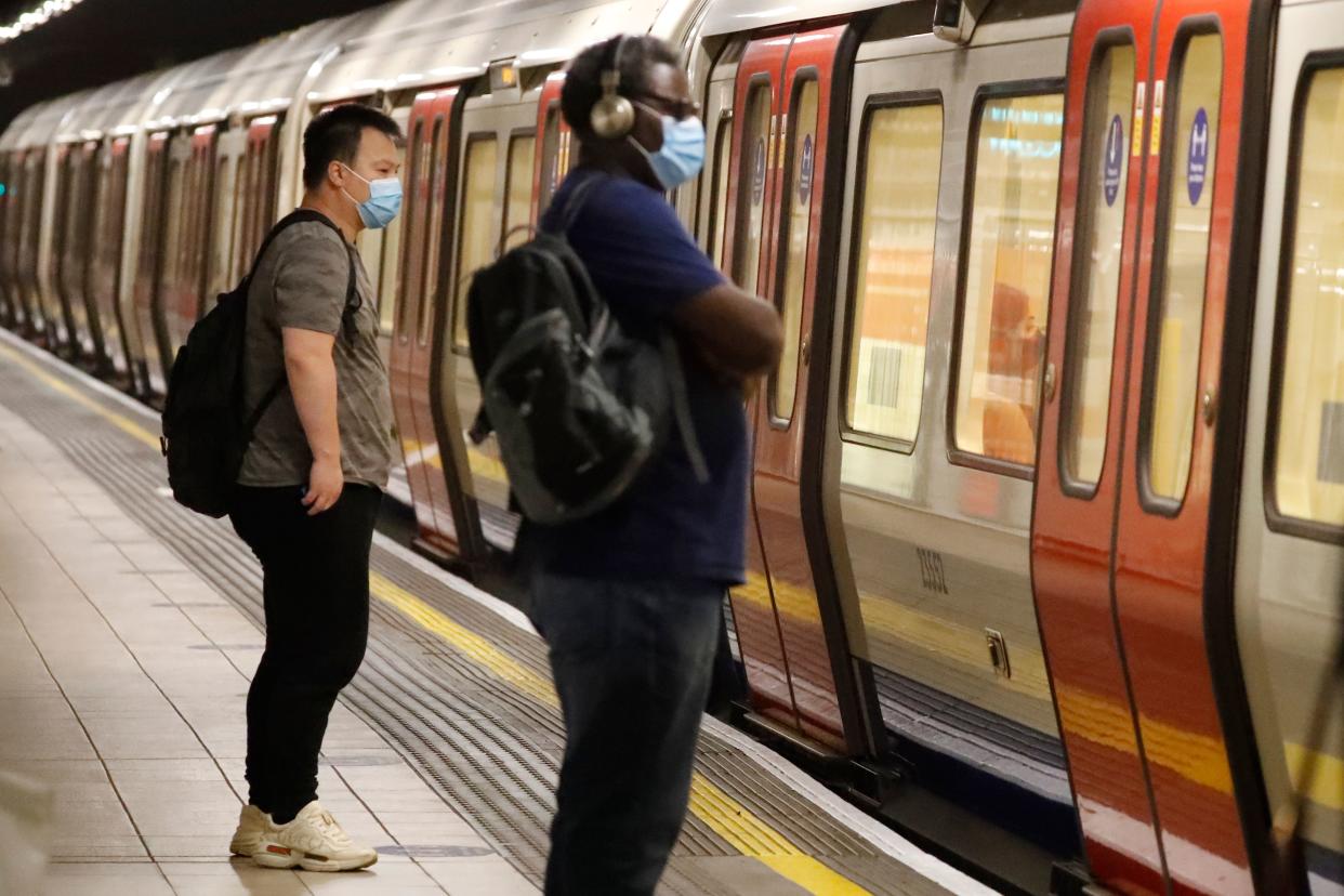 Passengers wear face masks as a precaution against the transmission of the novel coronavirus as they wait on an London Underground station platform in London on July 17, 2020. - Boris Johnson said on July 17 he hoped Britain would "return to normality" by November despite being badly affected by the coronavirus and predictions of a second wave of cases during winter months. Johnson sketched out a timetable for easing the remaining lockdown measures in England, including lifting homeworking guidance and reopening sports stadiums and live theatre. (Photo by Tolga AKMEN / AFP) (Photo by TOLGA AKMEN/AFP via Getty Images)