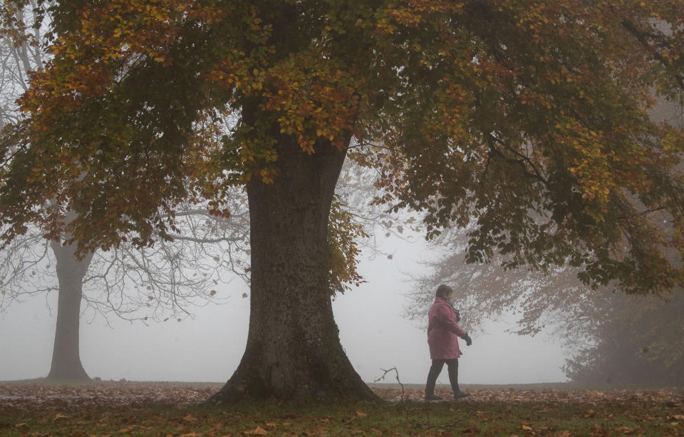 A lady walks through the fog in the War Memorial Park in Basingstoke, Hampshire.