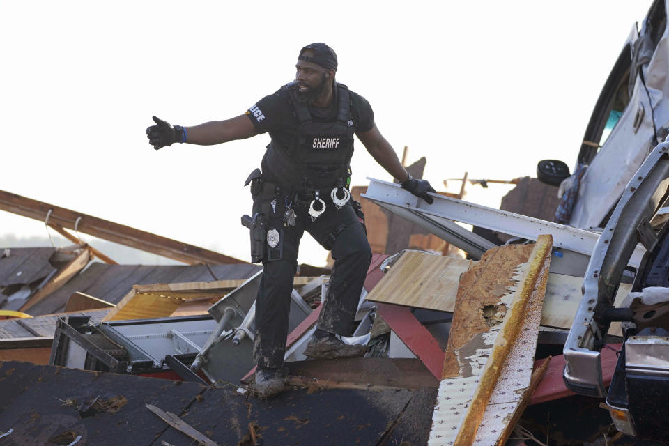 A sheriff's deputy gives the all clear signal after climbing onto a piled up vehicle to search for survivors or the deceased at Chuck's Dairy Bar in Rolling Fork, Miss., Saturday, March 25, 2023. Emergency officials in Mississippi say several people have been killed by tornadoes that tore through the state on Friday night, destroying buildings and knocking out power as severe weather produced hail the size of golf balls moved through several southern states. (AP Photo/Rogelio V. Solis)