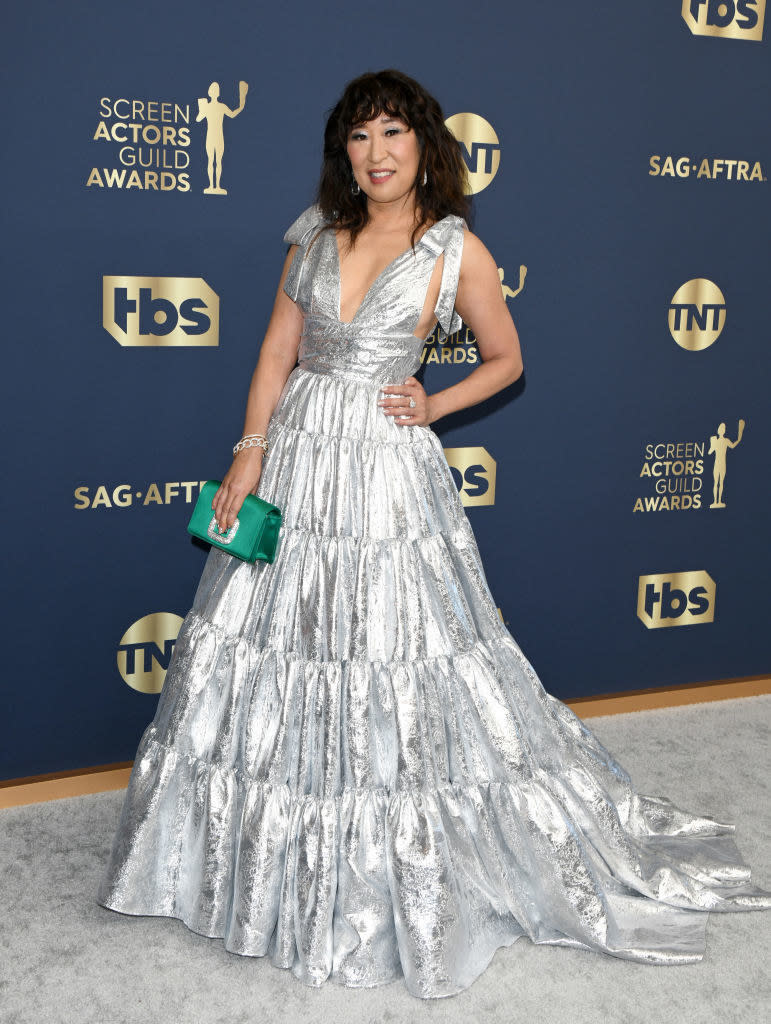 a metallic, floor-length halter gown with a deep-V neckline and a pleated, tiered skirt