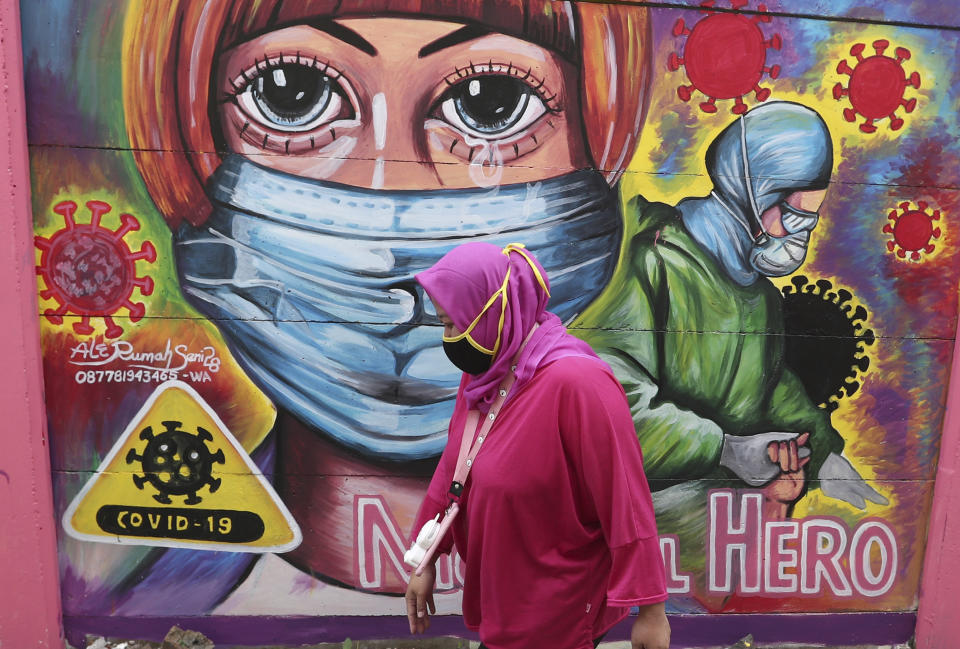 A woman walks past a coronavirus-themed mural honoring health workers in Tangerang, Indonesia, Tuesday, Jan. 26, 2021. Indonesia has reported more cases of the virus than any other countries in Southeast Asia. (AP Photo/Tatan Syuflana)