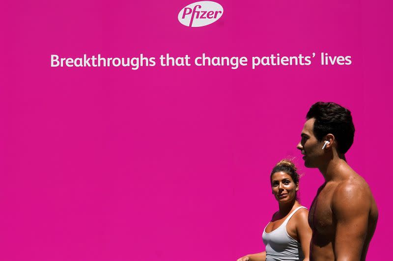 FILE PHOTO: People walk past a sign outside Pfizer Headquarters in the Manhattan borough of New York City