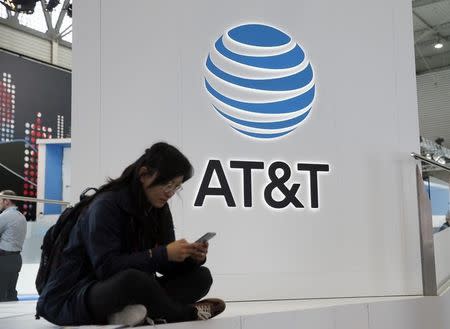 A woman looks at her mobile next to AT&T logo during the Mobile World Congress in Barcelona, Spain February 25, 2016. REUTERS/Albert Gea