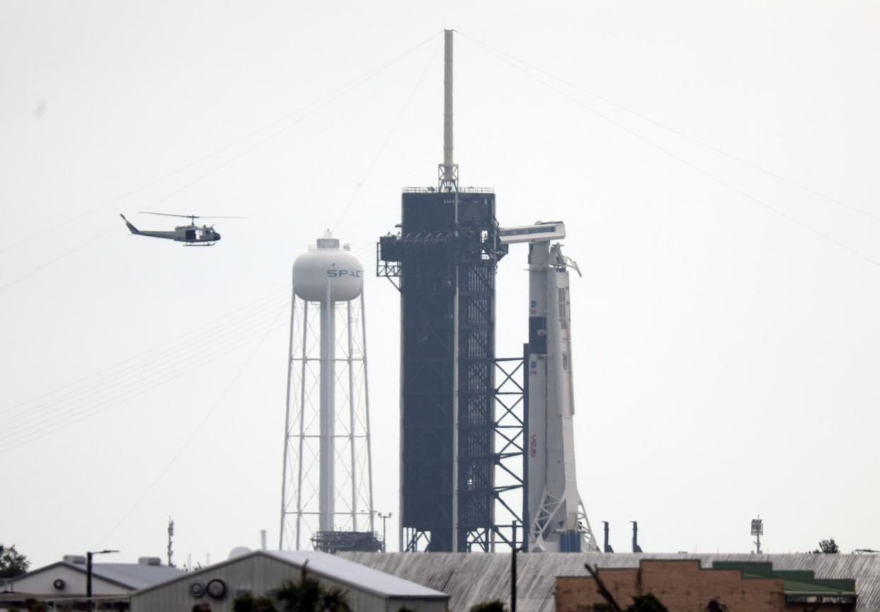 NASA security helicopter flies past launch complex 39A and the SpaceX Falcon 9 rocket with Crew Dragon vehicle on launch day at the Kennedy Space Center in Florida on May 26, 2020. - A new era in space begins Wednesday with the launch by SpaceX of two NASA astronauts into space, a capability that for six decades symbolized the power of a handful of states, and which the United States itself had been deprived of for nine years.If the bad weather clears, at 4:33 pm (20:33 GMT) a SpaceX rocket with the new Crew Dragon capsule on top will take off from Launch Pad 39A at the Kennedy Space Center, the same from which Neil Armstrong and his Apollo crewmates left for their historic journey to the Moon. (Photo by Gregg Newton / Gregg Newton / AFP) (Photo by GREGG NEWTON/Gregg Newton/AFP via Getty Images)