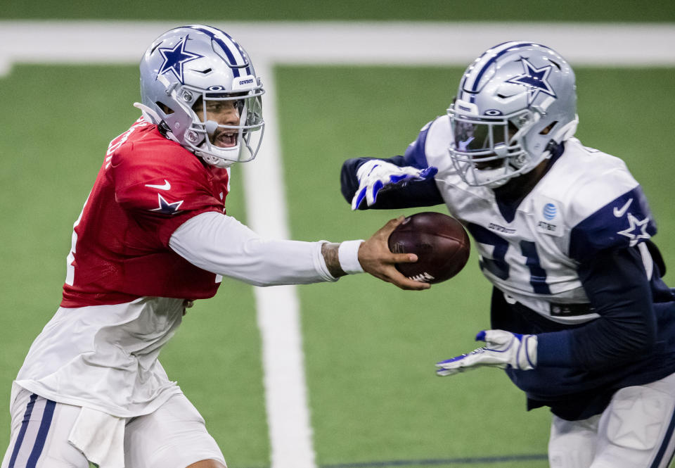 Dallas Cowboys quarterback Dak Prescott, left, hands the ball off to running back Ezekiel Elliott during an NFL football training camp practice at The Star, Friday, Aug. 28, 2020, in Frisco, Texas. (AP Photo/Brandon Wade)