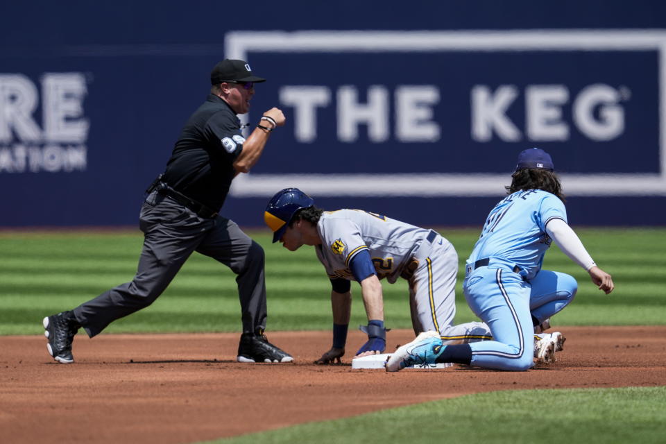 Toronto Blue Jays shortstop Bo Bichette, right, tags out Milwaukee Brewers designated hitter Christian Yelich on a steal attempt in the first inning of a baseball game in Toronto, Thursday, June 1, 2023. (Andrew Lahodynskyj/The Canadian Press via AP)