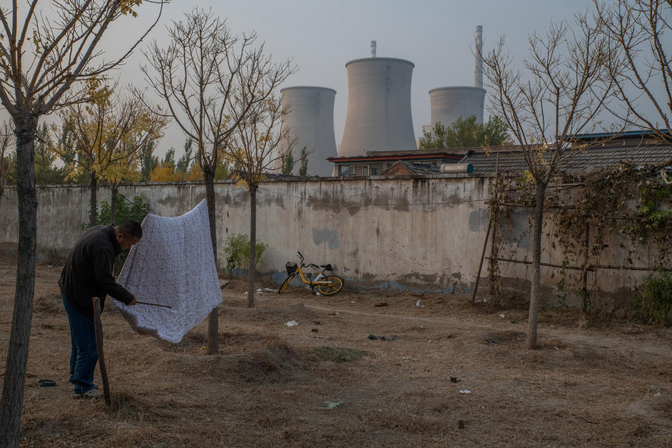 A man dusts off a comforter near a coal-fired power plant in Beijing on Oct. 25, 2022.<span class="copyright">Gilles Sabrié—The New York Times/Redux</span>