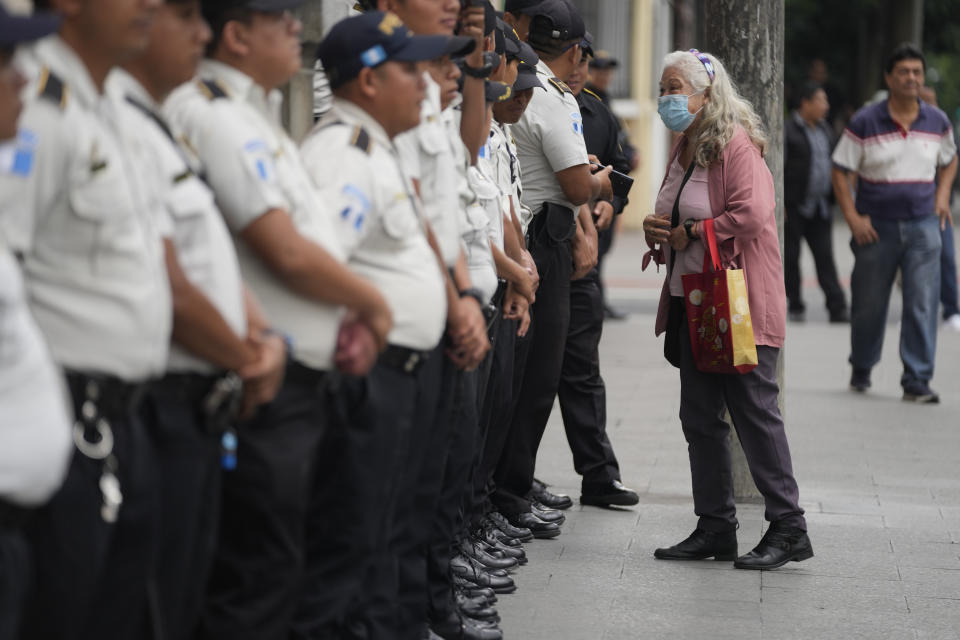 Una mujer se para a hablar con la policía que custodia el perímetro del edificio del Tribunal Supremo Electoral en Ciudad de Guatemala, el miércoles 30 de agosto de 2023. El candidato progresista Bernardo Arévalo fue proclamado el lunes presidente electo tras ganar la segunda vuelta electoral por el TSE, pero el mismo día el registro electoral dispuso la suspensión de su partido político. (AP Foto/Moisés Castillo)