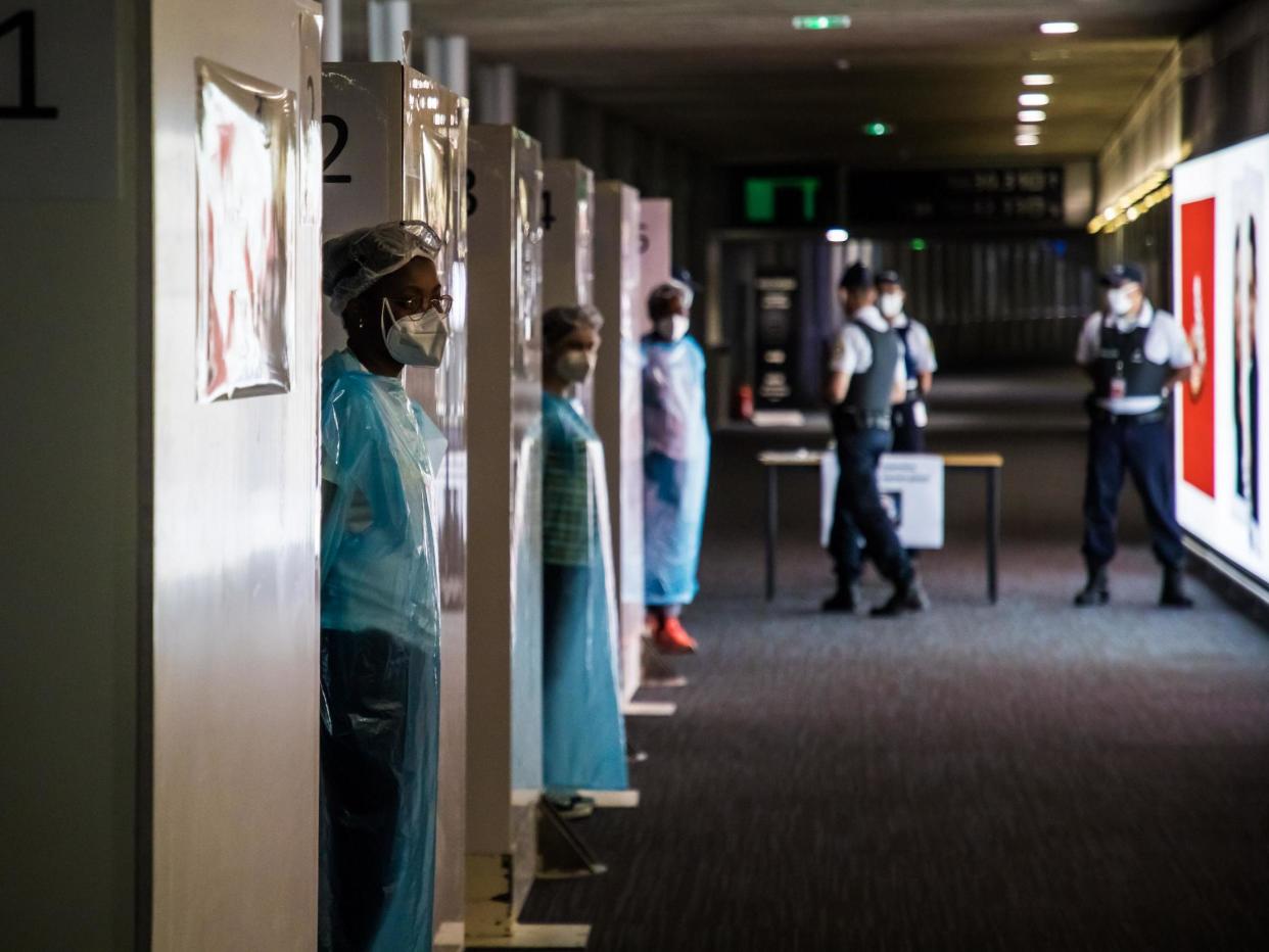 Health workers wearing protective gear wait for incoming travellers at Paris's Charles de Gaulle airport: Christophe Petit Tesson/POOL/AFP via Getty Images