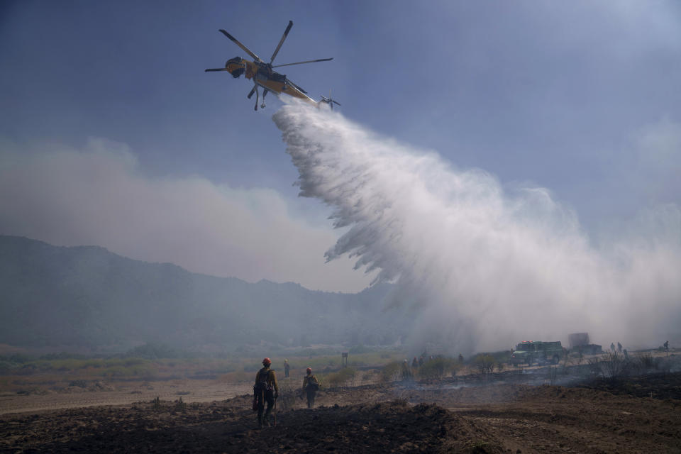 Un helicóptero arroja agua para combatir un incendio el domingo 16 de junio de 2024, en Lebec, California. (AP Foto/Eric Thayer)