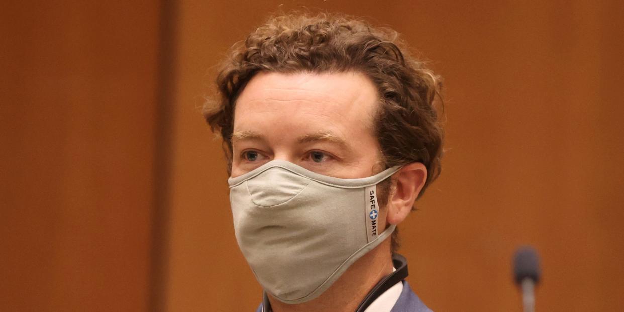 Danny Masterson stands in court with a mask on his face.