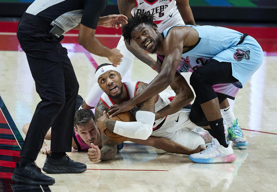 Miami Heat forward Jimmy Butler, right, and Portland Trail Blazers guard Damian Lillard look toward the referee after tying up with the ball during the first half of an NBA basketball game in Portland, Ore., Sunday, April 11, 2021. (AP Photo/Craig Mitchelldyer)