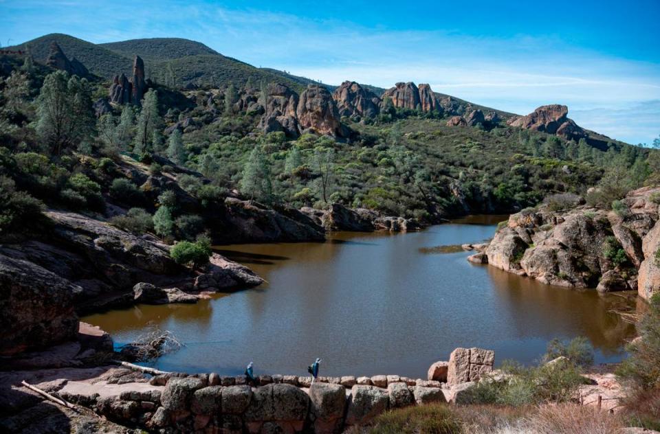 Hikers cross the Bear Gulch Reservoir dam as seen from the Rim Trail in Pinnacles National Park in Feburary 2021.