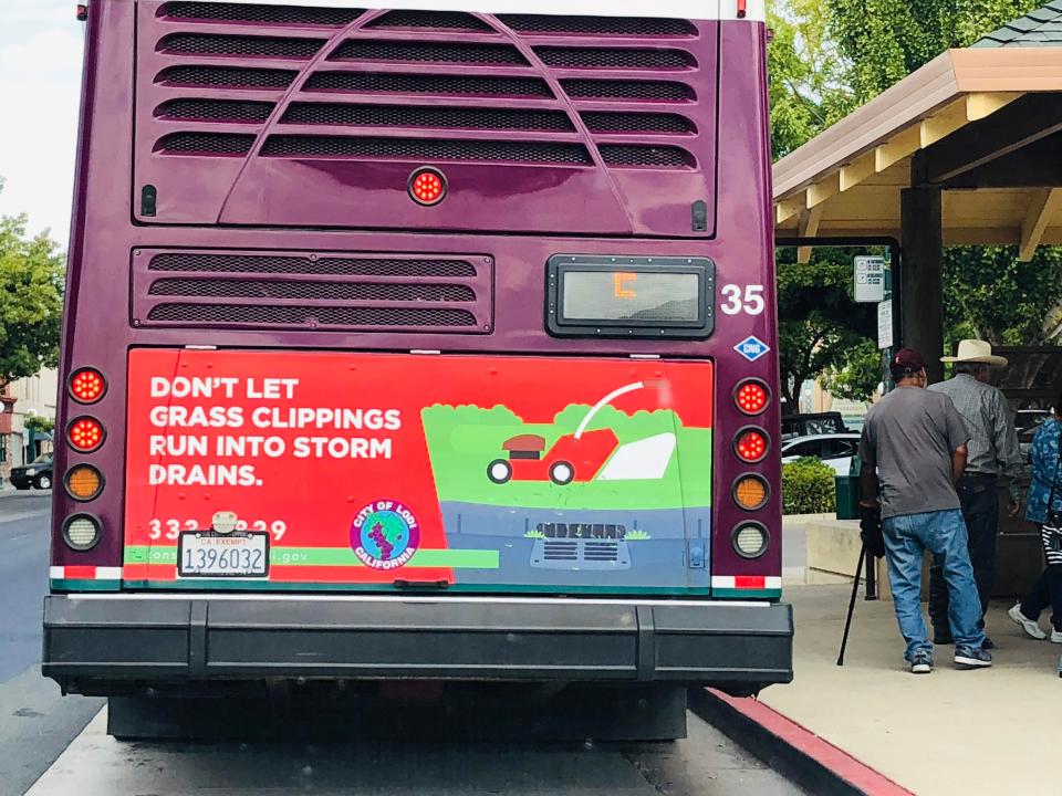 A bus sign carries an important reminder — "don't let grass clippings run into storm drains."