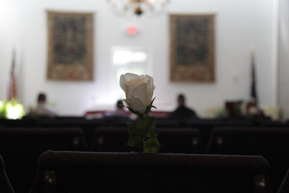 In this Friday, April 3, 2020, photo, a white rose is pinned to an empty chair during J. Robert Coleman's funeral in Lexington, S.C. Thompson Funeral Homes added the flowers to represent the loved ones who couldn't attend in the midst of the coronavirus pandemic. (AP Photo/Sarah Blake Morgan)