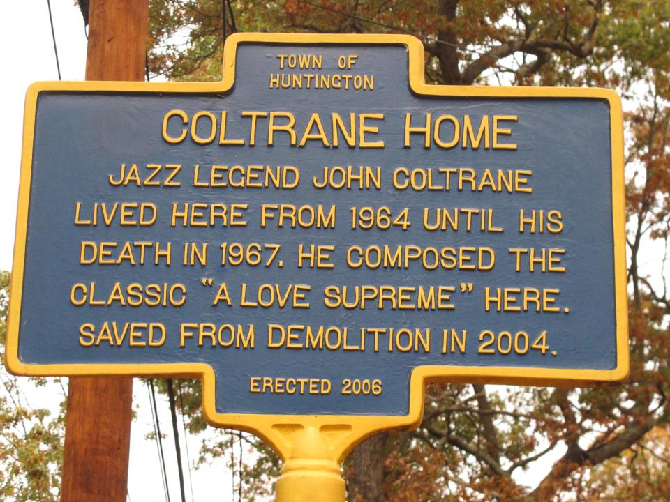 This Wednesday, Oct. 23, 2013 photo shows a historical marker outside the Dix Hills, N.Y. home of jazz legend John Coltrane. The move to restore the home began about a decade earlier when local jazz enthusiast Steve Fulgoni learned a developer had purchased the property with plans to demolish the home and build three smaller houses. He organized a lobbying effort to save the home, and eventually Huntington town officials purchased the property from the developer for $975,000 and designated it as a town park. (AP Photo/Frank Eltman)